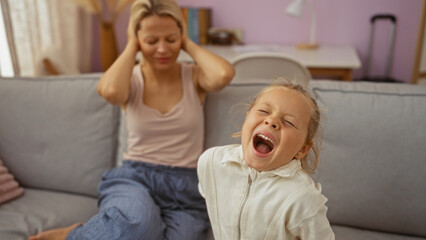 Obraz premium Woman with blonde hair stressed as daughter screams in indoor home living room
