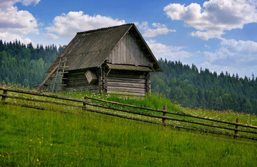 a wooden Hutsul barn made of logs and a fence in the Carpathian mountains