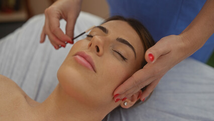 A therapist performs a facial massage on a relaxed woman in a spa, capturing a serene beauty and wellness setting indoors.