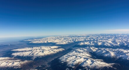Fototapeta premium Breathtaking aerial view of -capped mountains blue sky