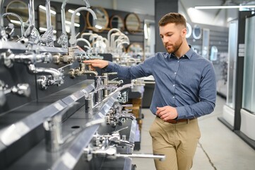 a customer in a hardware store in the plumbing department chooses a faucet for the kitchen