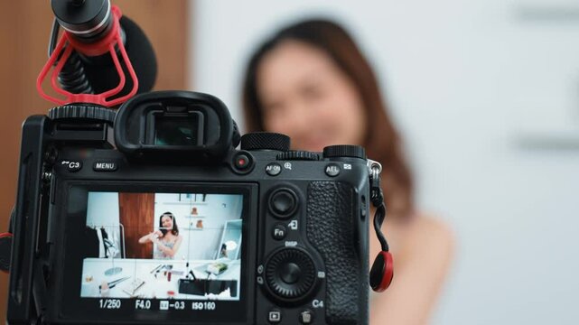 Rear view behide camera screen display woman influencer shoot live streaming vlog video review skincare social media or blog. Girl with cosmetic vivancy studio lighting for marketing recording.