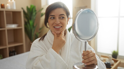 Woman admiring her reflection in a spa setting while wearing a white bathrobe, emphasizing relaxation and wellness indoors for a beauty treatment.