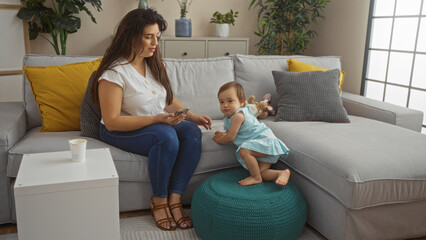 Mother and daughter sitting together on a couch in a cozy living room, showcasing family love and an indoor family moment.