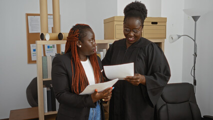 Black women lawyer and judge discussing documents in an office, showcasing a professional legal...