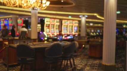 Blurred view inside las vegas casino featuring defocused slot machines and people under ambient lighting with bokeh effect creating a vibrant, energetic atmosphere. © Krakenimages.com