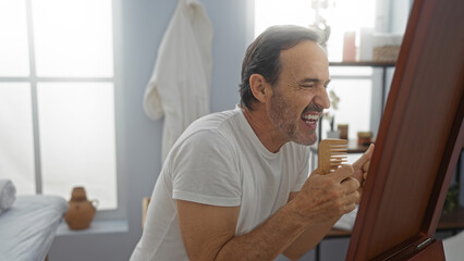 Hispanic man joyfully sings into a comb like a microphone in a serene spa setting, capturing the playful moment with a hint of relaxation.