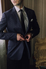 A man in a suit is adjusting his tie. Concept of formality and professionalism