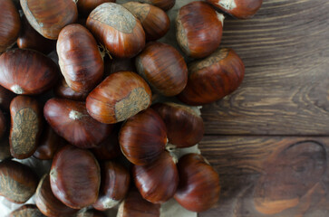 Edible raw chestnuts on brown paper on the table. The concept of autumn food. Street food. Selective focus. Horizontal orientation. Top view. Copy space