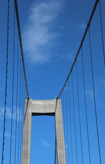 Obraz premium reinforced concrete pillar of the suspension bridge with the robust steel cable stays and the blue sky