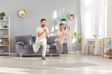 Fototapeta premium Family couple of an athletes, exercises together at home, performing squats. Fitness routine showcases commitment to an active sporty lifestyle, promoting health and wellness within the family.