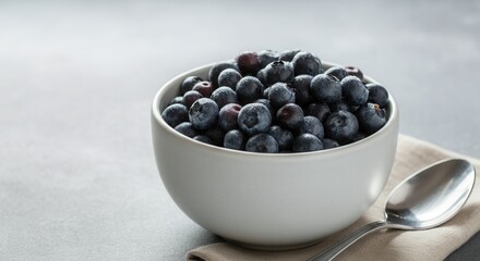 Fresh blueberries in white bowl with silver spoon