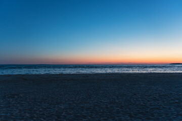 Obraz premium Serene beach at sunset with calm waves and distant horizon