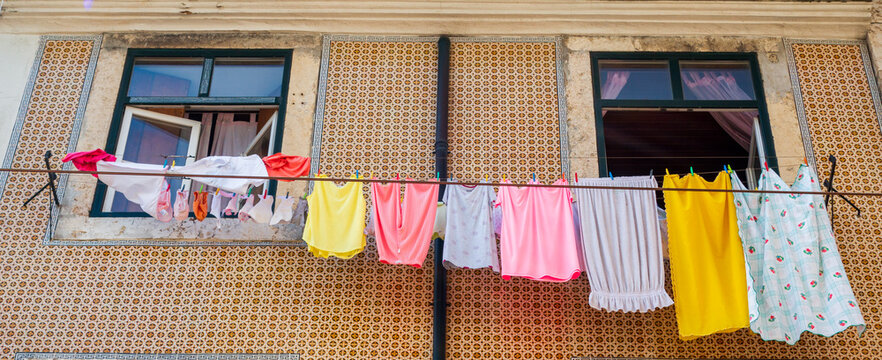 Colorful laundry hanging on traditional Lisbon tiled facade