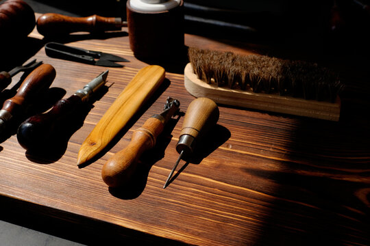 Traditional tools for handcrafted leather goods on wooden table