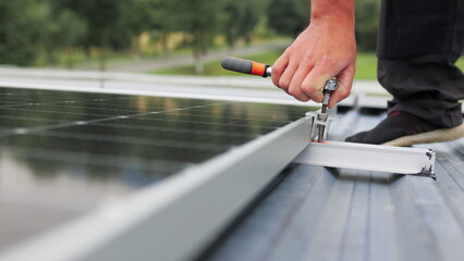 Mounting solar panel, installing solar panels on the roof of the house. Connection of solar panels. Close up of worker installing and working on maintenance of photovoltaic panel system installed