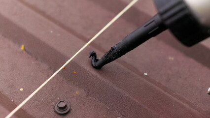 Close up of applying sealant on the roof. Carpenter repairing cabin roof of boat sealing leaks with mastic waterproof sealant