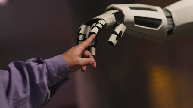Close-up hand of unrecognizable man touching finger of white robot. Cooperation. Futuristic lifestyle concept. Machine learning. Humanoid robot arm and human connection. Camera moving around. Parallax