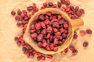 Dried cranberries with wooden utensils on a wooden table and top view, macro.