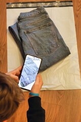 Selling or returning clothes; Close up of a person taking photos of jeans before packaging