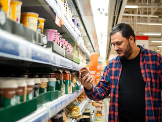 A man examines a ready to drink coffee container from the refrigerated section while shopping in a...