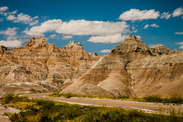 The road curves through and around the terrain within the Badlands National Park, South Dakota
