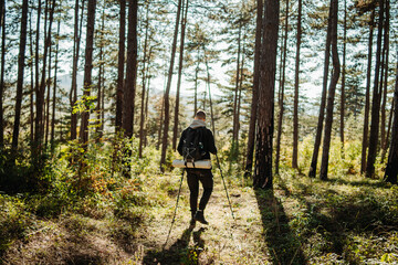 Young caucasian man hiking or trekking through the forest	