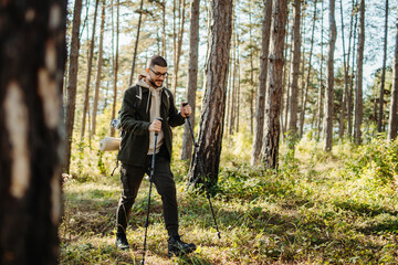 Fototapeta premium Young caucasian man hiking or trekking through the forest 