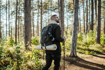 Fototapeta premium Young caucasian man hiking or trekking through the forest 