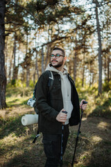 Young caucasian man hiking or trekking through the forest	