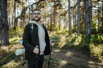Young caucasian man hiking or trekking through the forest	