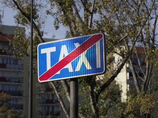 No stopping taxi sign on a city street with cars and buildings