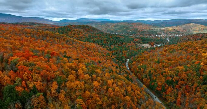 Picturesque wooded landscape covering mountainous landscape. Grey overcast sky above the autumn forest growing on rocks. Aerial view.