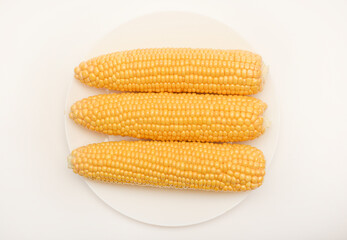 Ripe corn cobs on a white plate. Ripe vegetables.