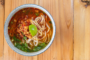 Khao Soi Chiang Tung is served in a bowl with sticky rice noodles and a flavorful soup that is Chiang Tung style. The delicious Khao Soi Chiang Tung is a popular noodle dish among Tai Yai people.
