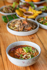 Khao Soi Chiang Tung is served in a bowl with sticky rice noodles and a flavorful soup that is Chiang Tung style. The delicious Khao Soi Chiang Tung is a popular noodle dish among Tai Yai people.