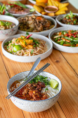 Khao Soi Chiang Tung is served in a bowl with sticky rice noodles and a flavorful soup that is Chiang Tung style. The delicious Khao Soi Chiang Tung is a popular noodle dish among Tai Yai people.