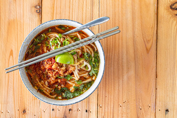 Khao Soi Chiang Tung is served in a bowl with sticky rice noodles and a flavorful soup that is Chiang Tung style. The delicious Khao Soi Chiang Tung is a popular noodle dish among Tai Yai people.