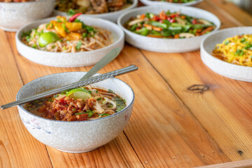 Khao Soi Chiang Tung is served in a bowl with sticky rice noodles and a flavorful soup that is Chiang Tung style. The delicious Khao Soi Chiang Tung is a popular noodle dish among Tai Yai people.