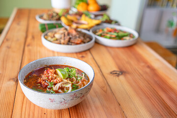 Khao Soi Chiang Tung is served in a bowl with sticky rice noodles and a flavorful soup that is Chiang Tung style. The delicious Khao Soi Chiang Tung is a popular noodle dish among Tai Yai people.