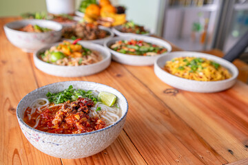Khao Soi Chiang Tung is served in a bowl with sticky rice noodles and a flavorful soup that is Chiang Tung style. The delicious Khao Soi Chiang Tung is a popular noodle dish among Tai Yai people.