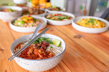 Khao Soi Chiang Tung is served in a bowl with sticky rice noodles and a flavorful soup that is Chiang Tung style. The delicious Khao Soi Chiang Tung is a popular noodle dish among Tai Yai people.