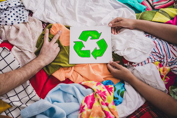 Young woman in living room with donation clothes and recycle symbol promoting environmental...