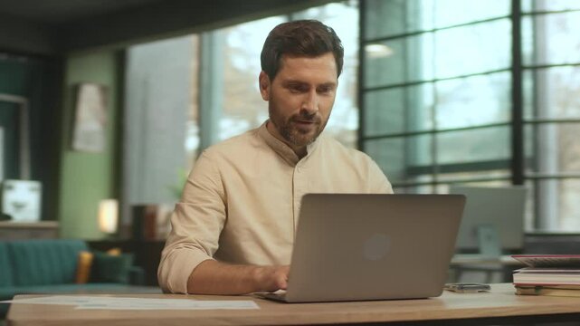 Happy businessman sitting at desk use laptop look on screen smiling and dance in office. Satisfied. Camera moving around. 360 Degree