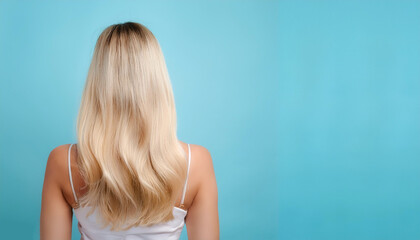 Obraz premium young woman with blonde hair standing with her back to the camera isolated on light blue pastel background