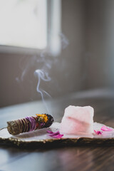 burning sage stick with smoke on platter with rose quartz
