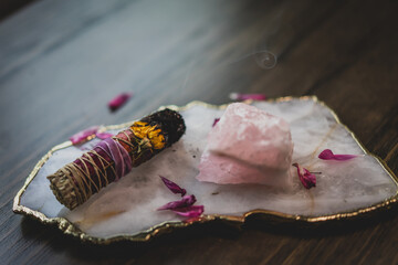 closeup of burnt sage smudge stick with crystals and flower petals