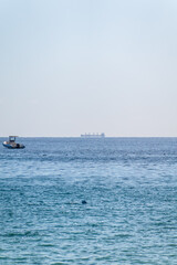 Calm blue sea with the silhouette of a large ship on the horizon