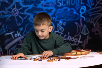 Boy working on a model ship with an instructional manual, engaging in a hands-on activity that...
