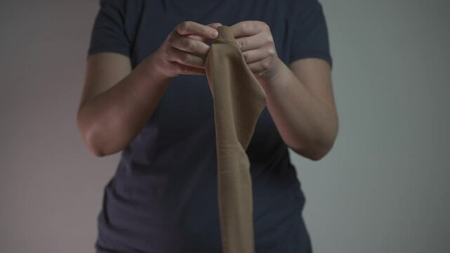 A woman puts on a compression sleeve on her arm to support vein health and prevent thrombosis. Compression helps improve circulation, reducing the risk of blood clots, varicose veins, and embolism. 